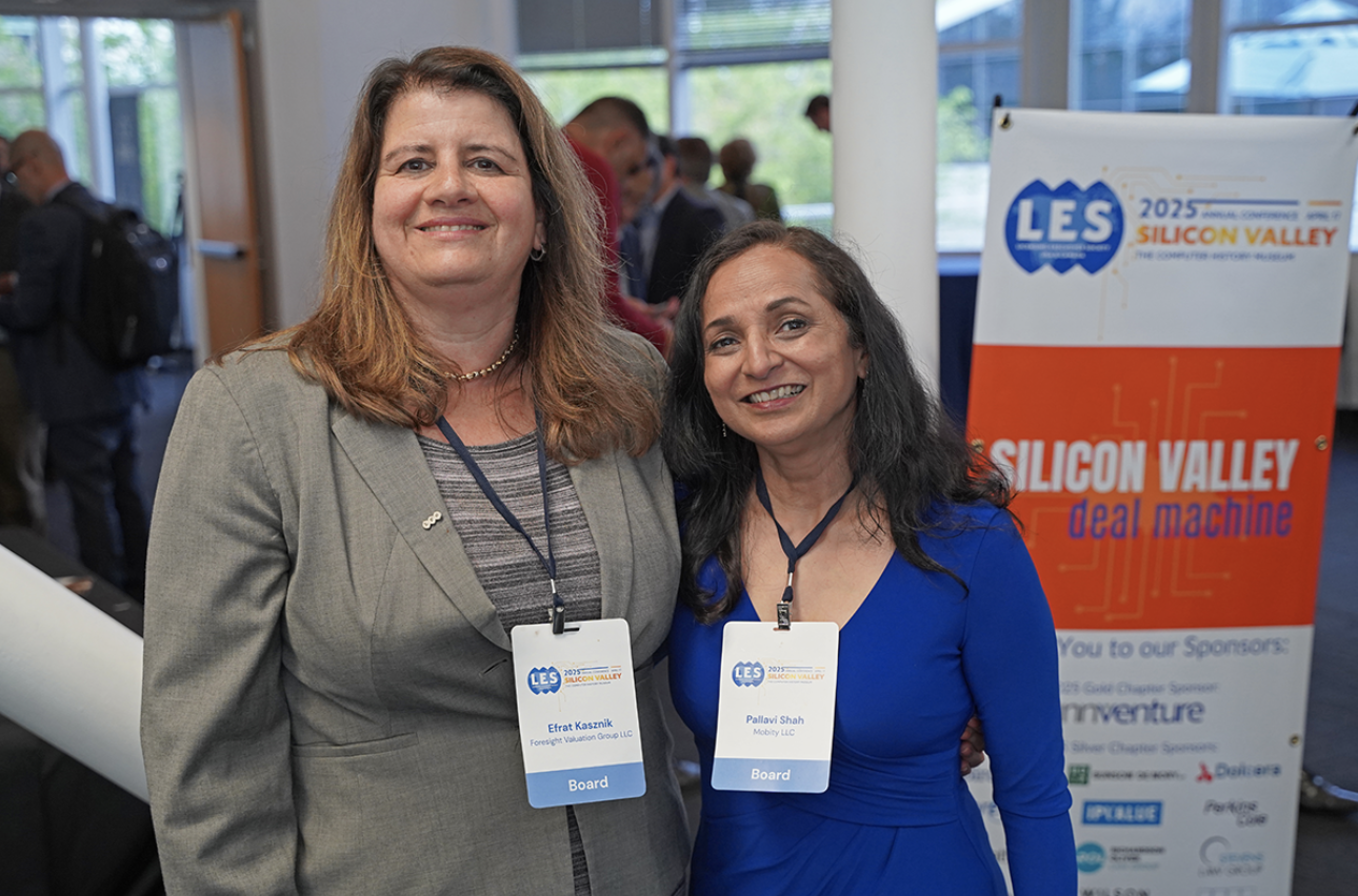 Efrat Kasznik and Pallavi Shah, two members of LES, pose by the poster for the Silicon Valley Deal Machine, an event hosted by the Silicon Valley Chapter, which brought together over 110 innovation leaders, IP professionals, and business dealmakers at the Computer History Museum in Mountain View, California.